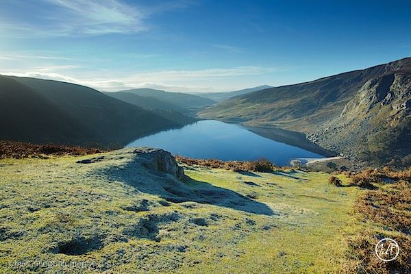The sun casts it's early morning rays upon the cliffs surrounding Lough Tay, Co. Wicklow in Ireland