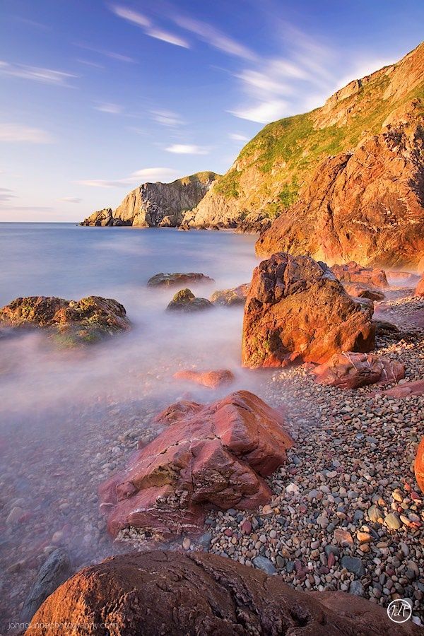 The early morning sun casts an amazing soft and warm light on the rocks in the foreground and cliffs behind at Howth in Dublin , Ireland