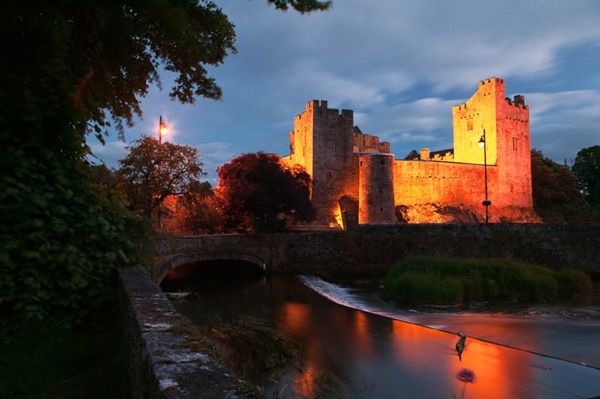 Midlands of Ireland: Tipperary: Cahir. Image of Cahir (or Caher) Castle in the evening, viewed from the weir on the River Suir. Cahir Castle is a very fine example of a late Medieval castle.  It was remodeled and extended in the 15th to 17th centuries.