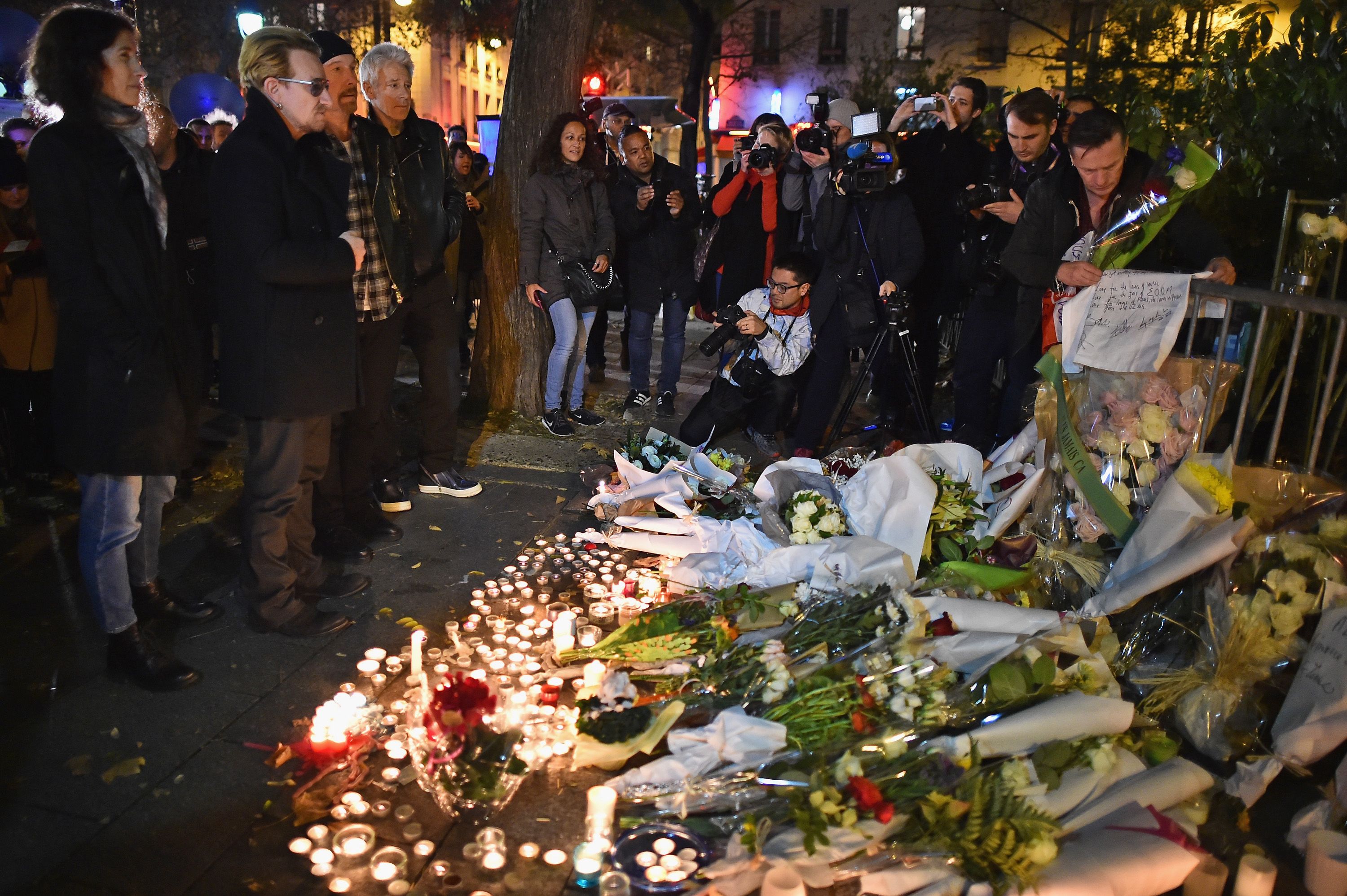 PARIS, FRANCE - NOVEMBER 14: Bono and The Edge of U2 place flowers on the pavement near the scene of yesterday's Bataclan Theatre terrorist attack on November 14, 2015 in Paris, France. At least 120 people have been killed and over 200 injured, 80 of which seriously, following a series of terrorist attacks in the French capital. (Photo by Jeff J Mitchell/Getty Images)