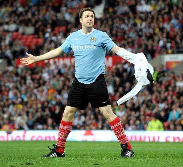 MANCHESTER, ENGLAND - MAY 01: Jason Manford strips off shirt to reveal rival team Manchester City shirt while playing football at United For Relief: The Big Red Family Day Out at Old Trafford on May 1, 2010 in Manchester, England. (Photo by Shirlaine Forrest/Getty Images)