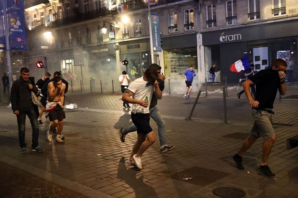 LILLE, FRANCE - JUNE 15: People cover their faces as they run after tear gas is fired as French riot police encounter hundreds of drunken English football fans on June 15, 2016 in Lille, France. Police used tear gas and pepper spray on the fans in a bid to keep public order in the city centre this evening. (Photo by Carl Court/Getty Images)