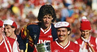 LONDON, UNITED KINGDOM - APRIL 05: Arsenal defender and captain Kenny Sansom holds the trophy, whilst Niall Quinn celebrates behind after the 1987 Littlewoods Cup Final victory against Liverpool at Wembley Stadium on April 5, 1987 in London, England. (Photo by Simon Bruty/Allsport/Getty Images)